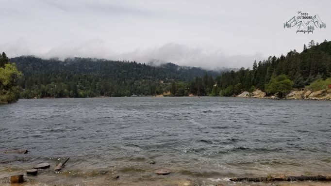 fog moving in over a forested mountain lake